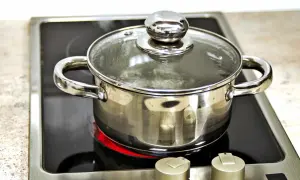 Garnek z wodą gotuje się na płycie indukcyjnej, pokazując, jak działa indukcja. Ciepło jest generowane bezpośrednio w naczyniu.