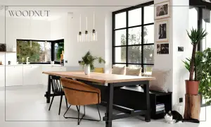 Nowoczesny salon loft inspiracje: drewniany stół, skórzane fotele, duża kuchnia i okna. Dwa koty odpoczywają przy ławie.