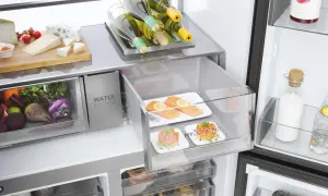 Wnętrze lodówki: świeże warzywa, sery, łosoś, tatary, butelki wina i napojów.
