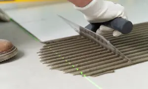 Równomierne rozprowadzanie kleju pod płytki za pomocą kielni. Precyzyjne linie kleju i zielona linia lasera zapewniają idealne ułożenie.