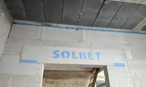 Dylatacja płytek od ściany wykonana pianką montażową. Widoczny napis "SOLBET" na bloczkach.