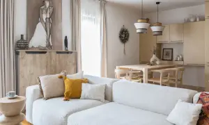 Jasny salon z sofą, stołem i krzesłami w stylu organic modern. Drewniane meble, naturalne tkaniny i subtelne dekoracje tworzą przytulną atmosferę.
