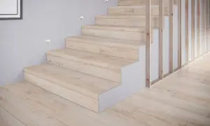 Schody z płytek drewnopodobnych w jasnym odcieniu, tworzące przytulne inspiracje. Drewniany balustrada i subtelne oświetlenie dodają elegancji.