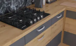 Nowoczesna kuchnia z czarną płytą gazową na blacie dąb artisan. Szare fronty szafek z metalowymi uchwytami.
