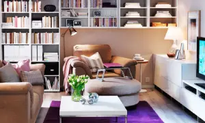 Małe mieszkanie inspiracje: przytulny salon z regałami pełnymi książek, wygodnym fotelem i stolikiem kawowym.