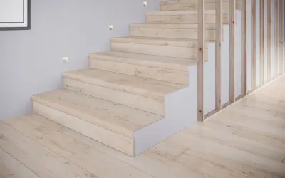 Schody z płytek drewnopodobnych w jasnym odcieniu, tworzące przytulne inspiracje. Drewniany balustrada i subtelne oświetlenie dodają elegancji.