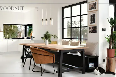 Nowoczesny salon loft inspiracje: drewniany stół, skórzane fotele, duża kuchnia i okna. Dwa koty odpoczywają przy ławie.