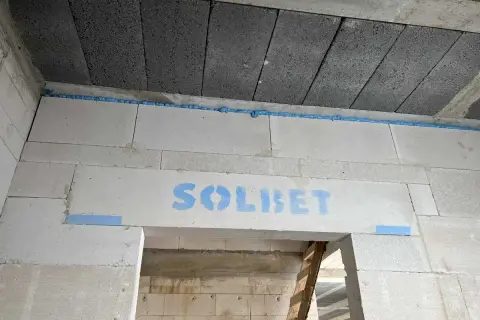Dylatacja płytek od ściany wykonana pianką montażową. Widoczny napis "SOLBET" na bloczkach.