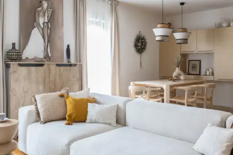 Jasny salon z sofą, stołem i krzesłami w stylu organic modern. Drewniane meble, naturalne tkaniny i subtelne dekoracje tworzą przytulną atmosferę.
