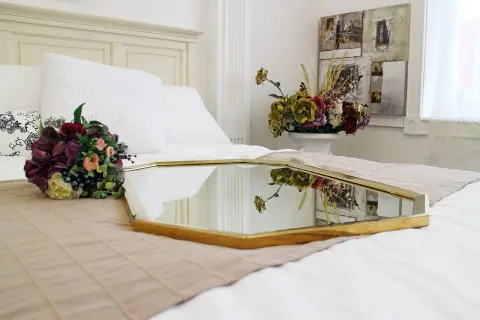 Eleganckie feng shui lustro na łóżku, odbijające bukiet kwiatów i dekoracje ścienne, tworzy harmonijną przestrzeń.