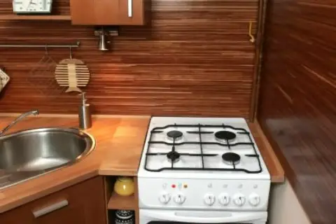 Biała kuchenka wolnostojąca obok zlewu, idealnie wpasowana w drewniany blat. Dowiedz się, jak połączyć blat z kuchenką wolnostojącą, by stworzyć funkcjonalną kuchnię.
