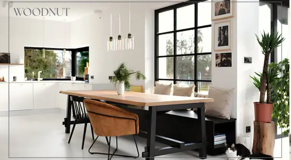 Nowoczesny salon loft inspiracje: drewniany stół, skórzane fotele, duża kuchnia i okna. Dwa koty odpoczywają przy ławie.