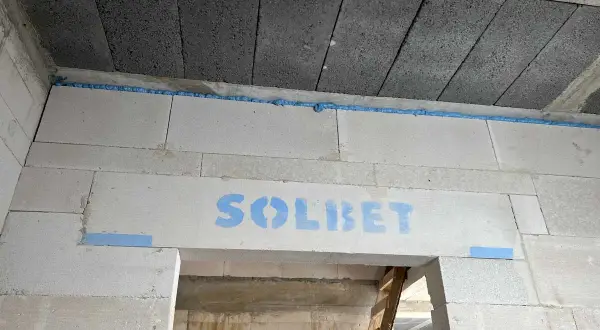 Dylatacja płytek od ściany wykonana pianką montażową. Widoczny napis "SOLBET" na bloczkach.