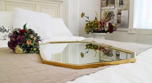 Eleganckie feng shui lustro na łóżku, odbijające bukiet kwiatów i dekoracje ścienne, tworzy harmonijną przestrzeń.