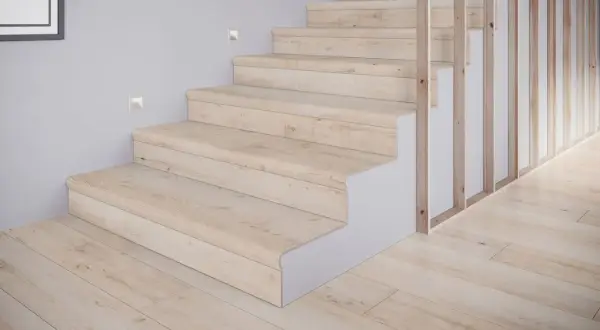 Schody z płytek drewnopodobnych w jasnym odcieniu, tworzące przytulne inspiracje. Drewniany balustrada i subtelne oświetlenie dodają elegancji.