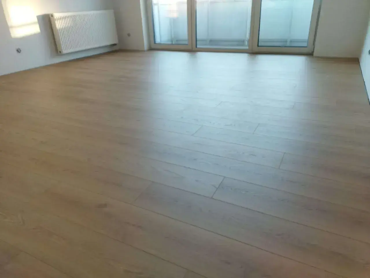 Nowe panele ułożone równolegle do okna, tworząc jasną i przestronną przestrzeń.
