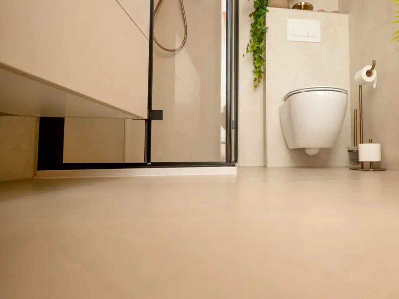 Nowoczesna łazienka z podwieszanym WC i prysznicem. Jasne ściany i podłoga tworzą spójną całość, a płytki na płytki dodają elegancji.