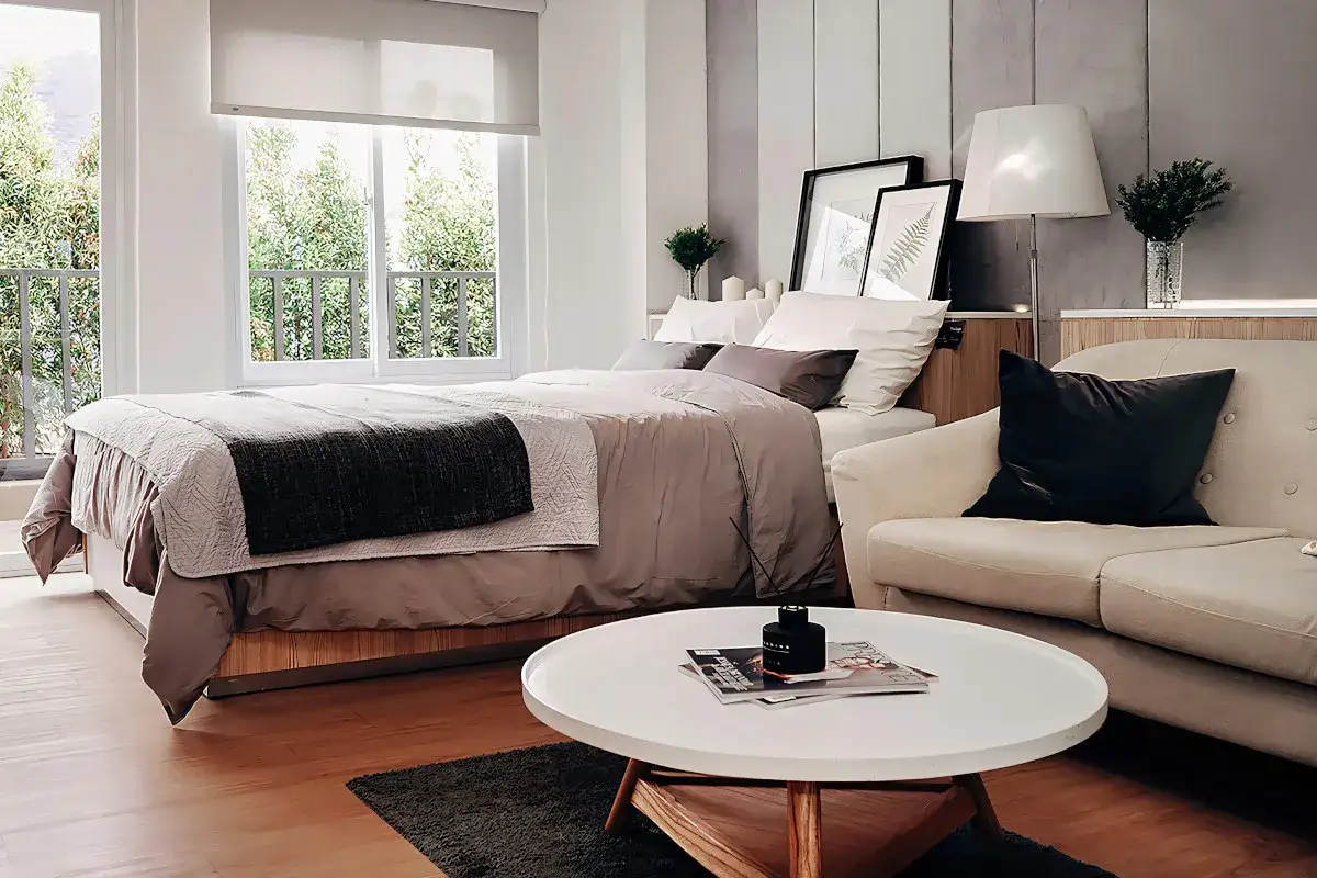 Elegancka sypialnia w salonie: ł&oacute;żko, sofa i stolik kawowy tworzą przytulną przestrzeń.