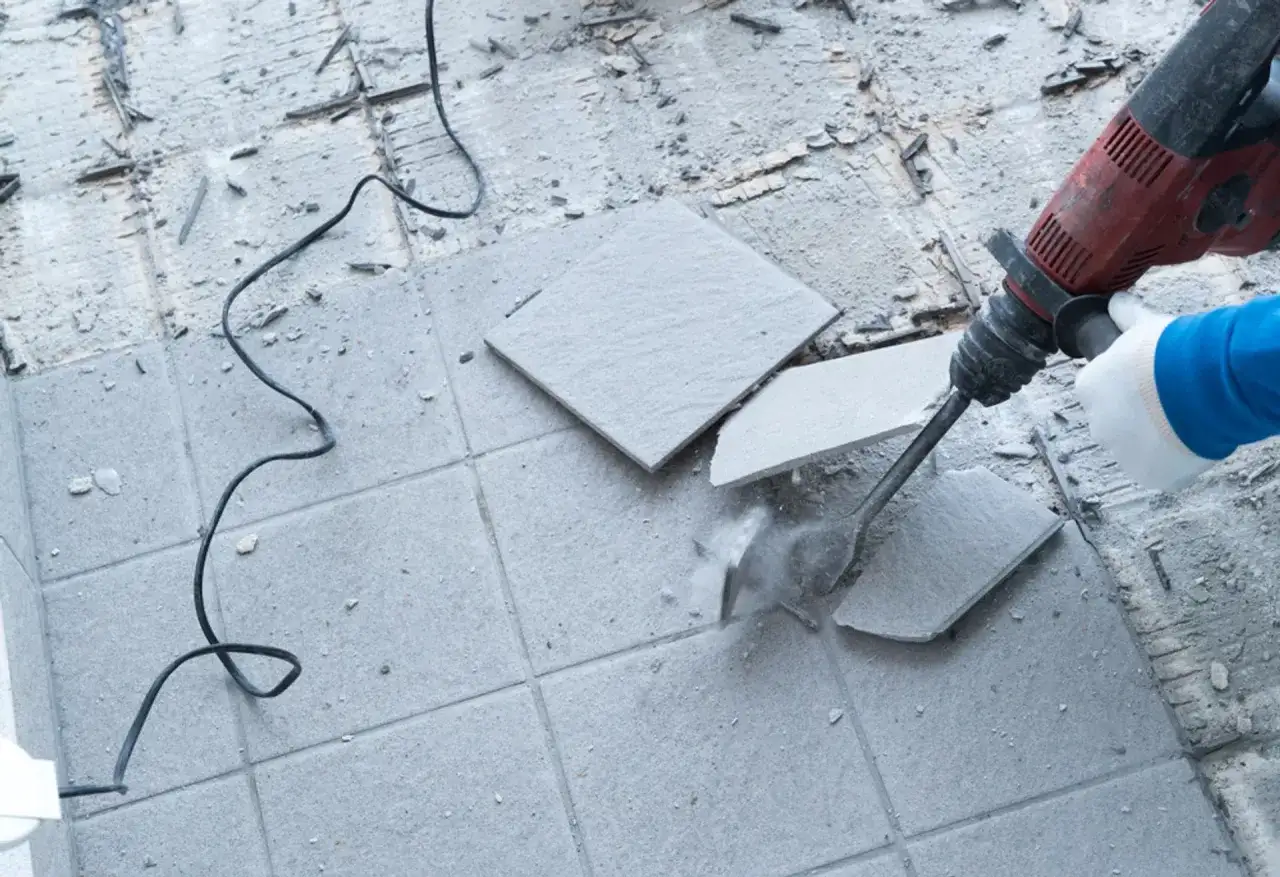 Rękawica i młot udarowy pomagają skuć płytki bez uszkodzenia podłogi.