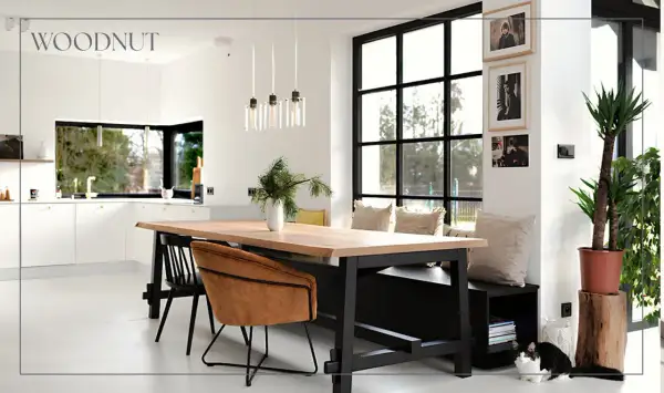 Nowoczesny salon loft inspiracje: drewniany stół, skórzane fotele, duża kuchnia i okna. Dwa koty odpoczywają przy ławie.