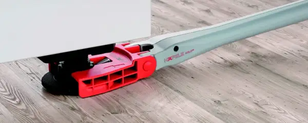 Czerwono-szara nóżka Hafele Axilo podtrzymuje biały mebel, opierając się na drewnianej podłodze.