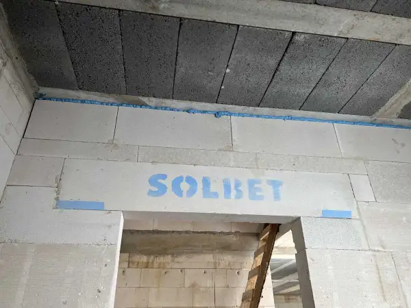 Dylatacja płytek od ściany wykonana pianką montażową. Widoczny napis "SOLBET" na bloczkach.