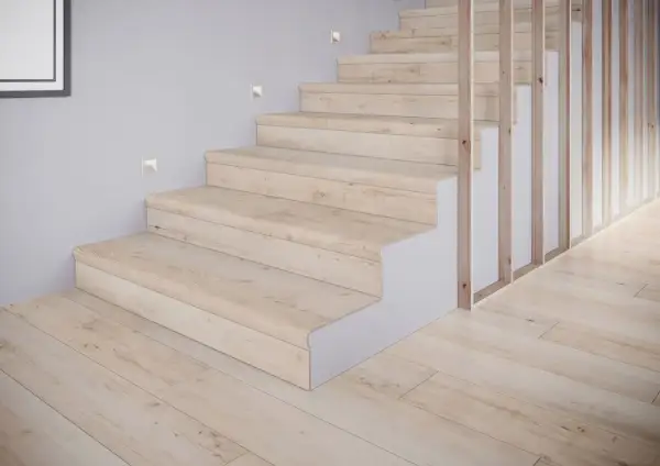 Schody z płytek drewnopodobnych w jasnym odcieniu, tworzące przytulne inspiracje. Drewniany balustrada i subtelne oświetlenie dodają elegancji.